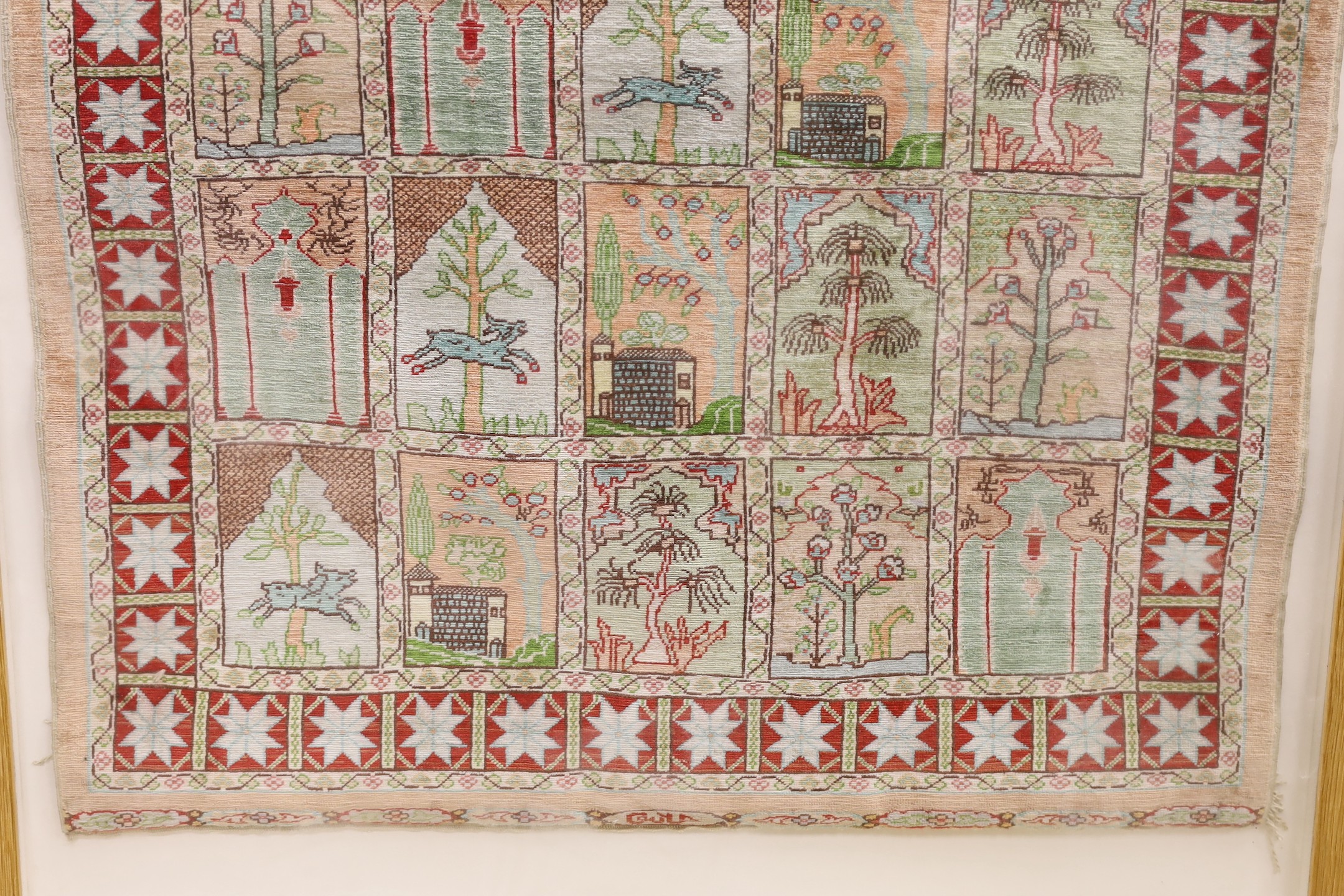 An Eastern framed silk rug depicting trees amimals and buildings, 86 cms high x 67cms wide